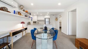A modern kitchen with white cabinets, a microwave, and a refrigerator.