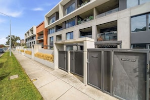A modern multi-story building with a flat roof, large windows, and a gated entrance. - Stylish 1-Bed Retreat in Braddon (Braddon)