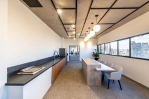 Eine moderne Küche mit einer langen Arbeitsfläche, einem Spülbecken und einem Essbereich mit Stühlen und einem Tisch.