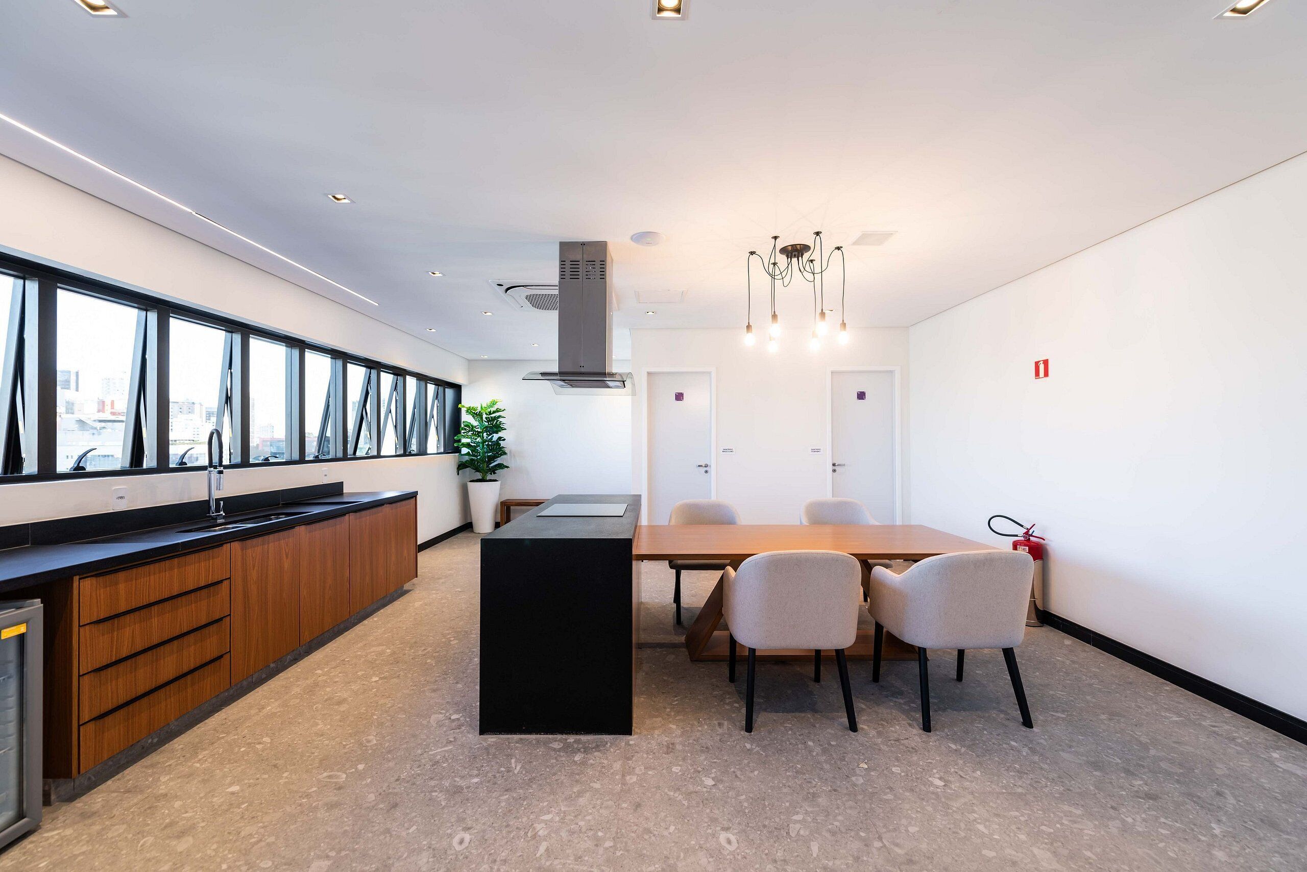 Una cocina moderna con una isla central, una mesa de comedor con sillas y vistas amplias a través de ventanas grandes.