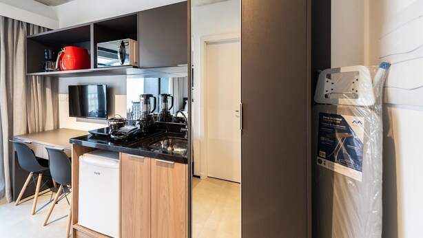 Una cocina compacta equipada con refrigerador, microondas y cafetera.