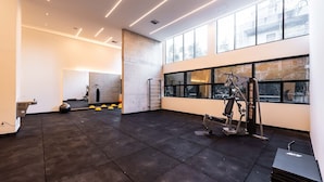 Un gimnasio espacioso con equipo de ejercicio, ventanas amplias y un techo alto.