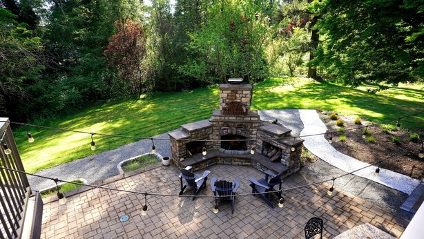 A stone fire pit with seating, surrounded by a brick patio, set in a lush garden. - Family Seattle Stay • Swim Spa • Fire Pit • 9 beds (Woodinville)