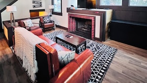 Een gezellige woonkamer met een open haard, een leren bank en een plafondventilator.