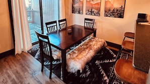 Een eetruimte met een houten tafel, stoelen, een kroonluchter en een bontje.