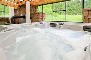Un bain à remous avec un intérieur en bois et une vue sur la verdure environnante.