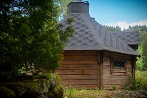 A wooden cabin with a thatched roof, surrounded by trees. - Self-catering group gîte for 30 people with swimming pool and jacuzzi (La Petite-Fosse)