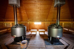 Un sauna équipé de deux grands radiateurs métalliques, de bancs en bois et d’un plancher en bois.