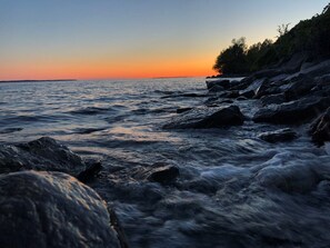 Un rivage rocheux, avec des vagues au coucher du soleil.