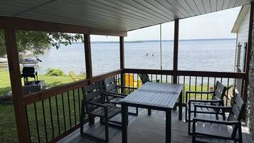 Une terrasse couverte, dotée d’une table et de chaises, qui offre une vue sur une étendue d’eau.