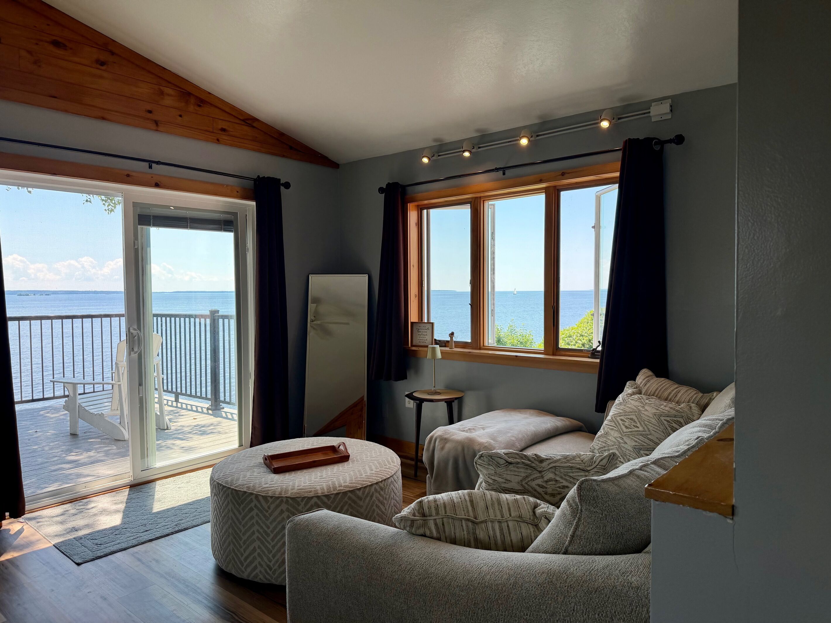 Une chambre avec un balcon, un canapé, une petite table et une fenêtre donnant sur la mer.