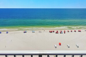 A beach with rows of umbrellas and beach chairs, a clear sky, and the ocean. - Windemere 1103 | Beachfront | Seasonally Heated Pool | My Beach Getaways (Pensacola)