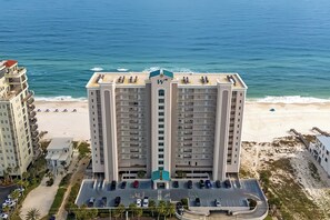 Ein Hochhaus-Hotel mit einem zentralen Turm, Parkplatz und Blick auf den Strand.