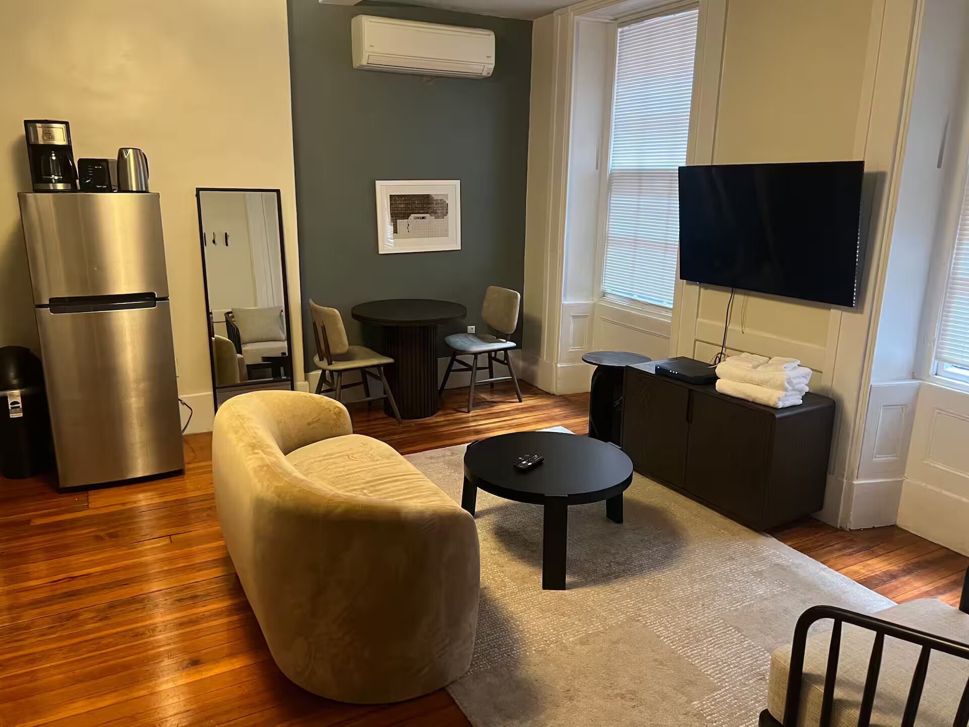 A living room with a sofa, coffee table, TV, and a small dining area.