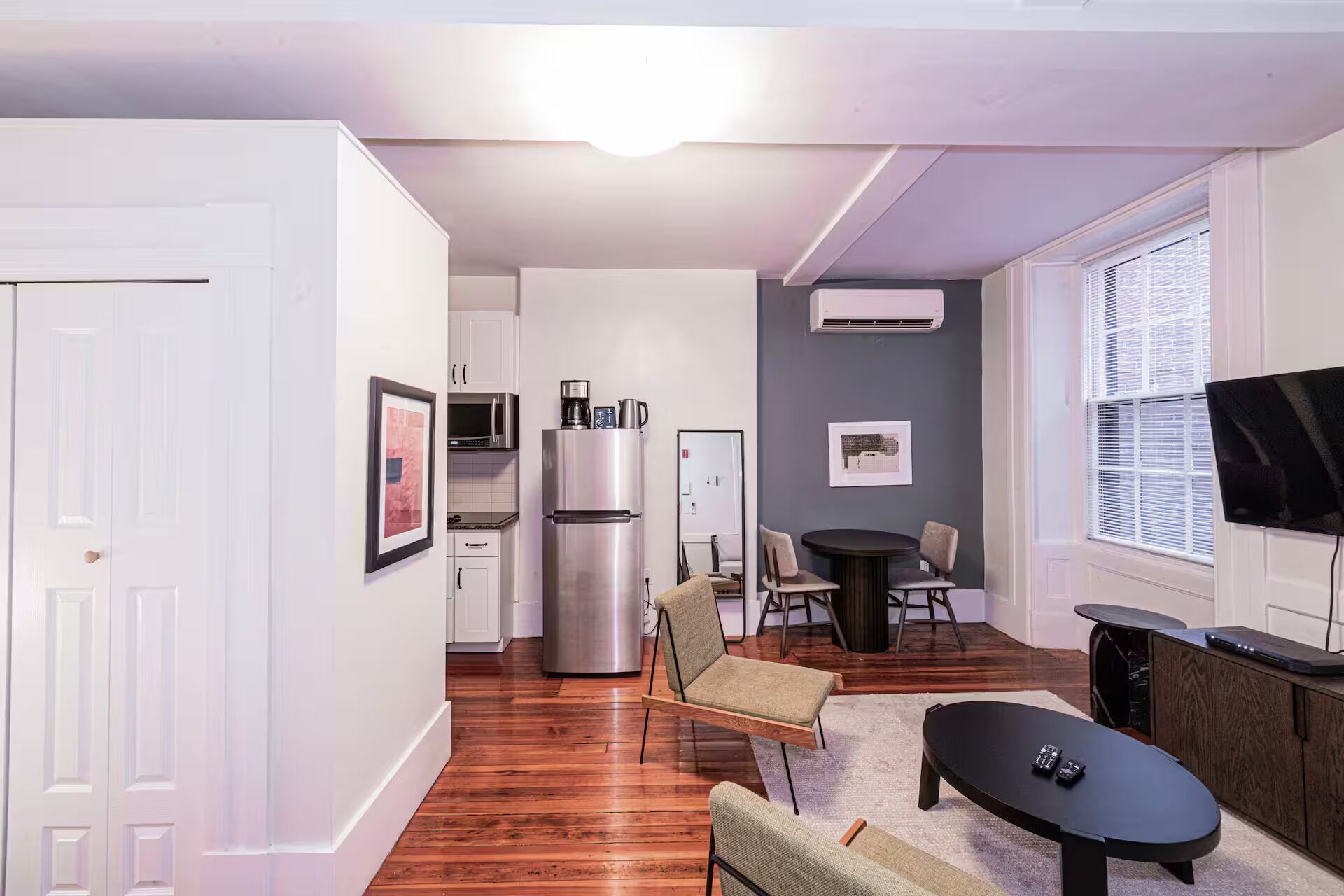 A compact living space with a kitchenette, a dining area, and a seating area with a TV.