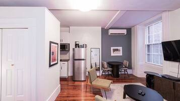 A compact living space with a kitchenette, a dining area, and a seating area with a TV.