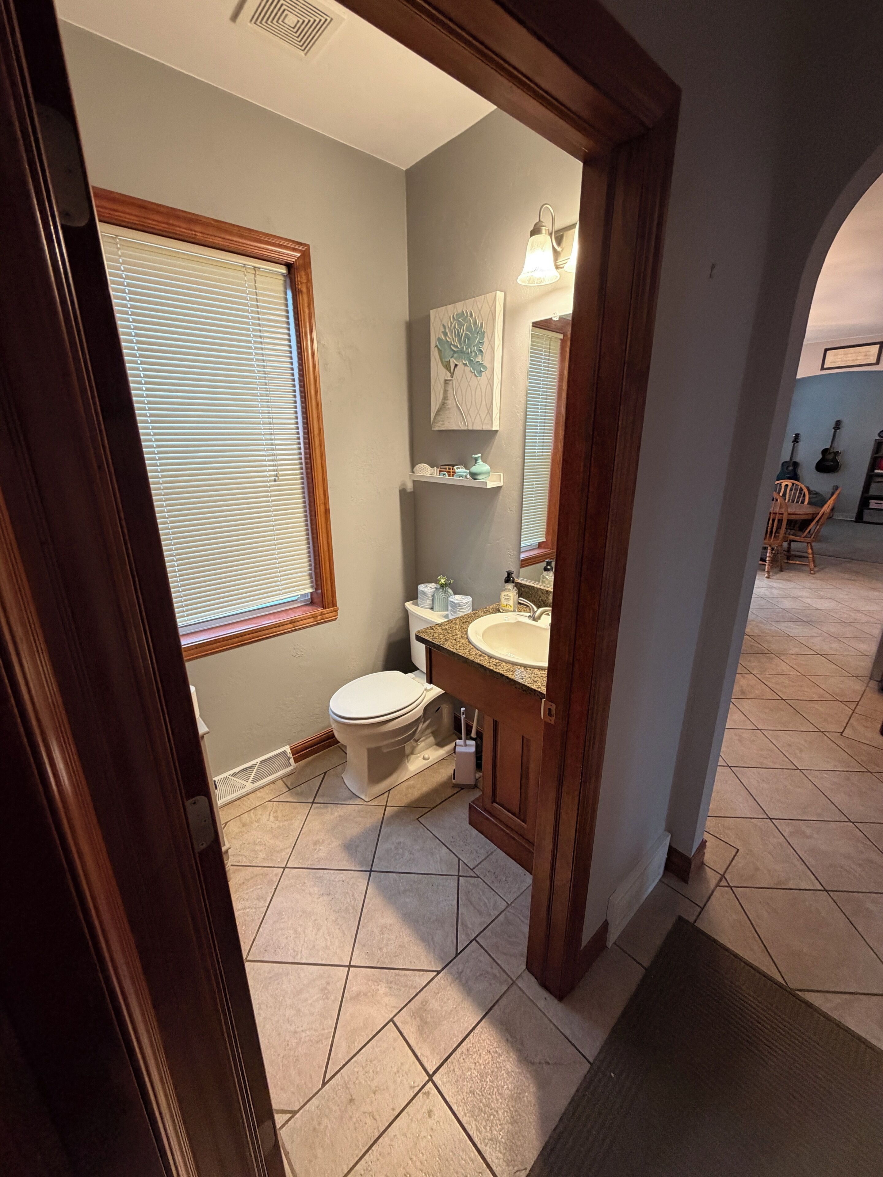 A bathroom with a toilet, sink, and window with blinds.