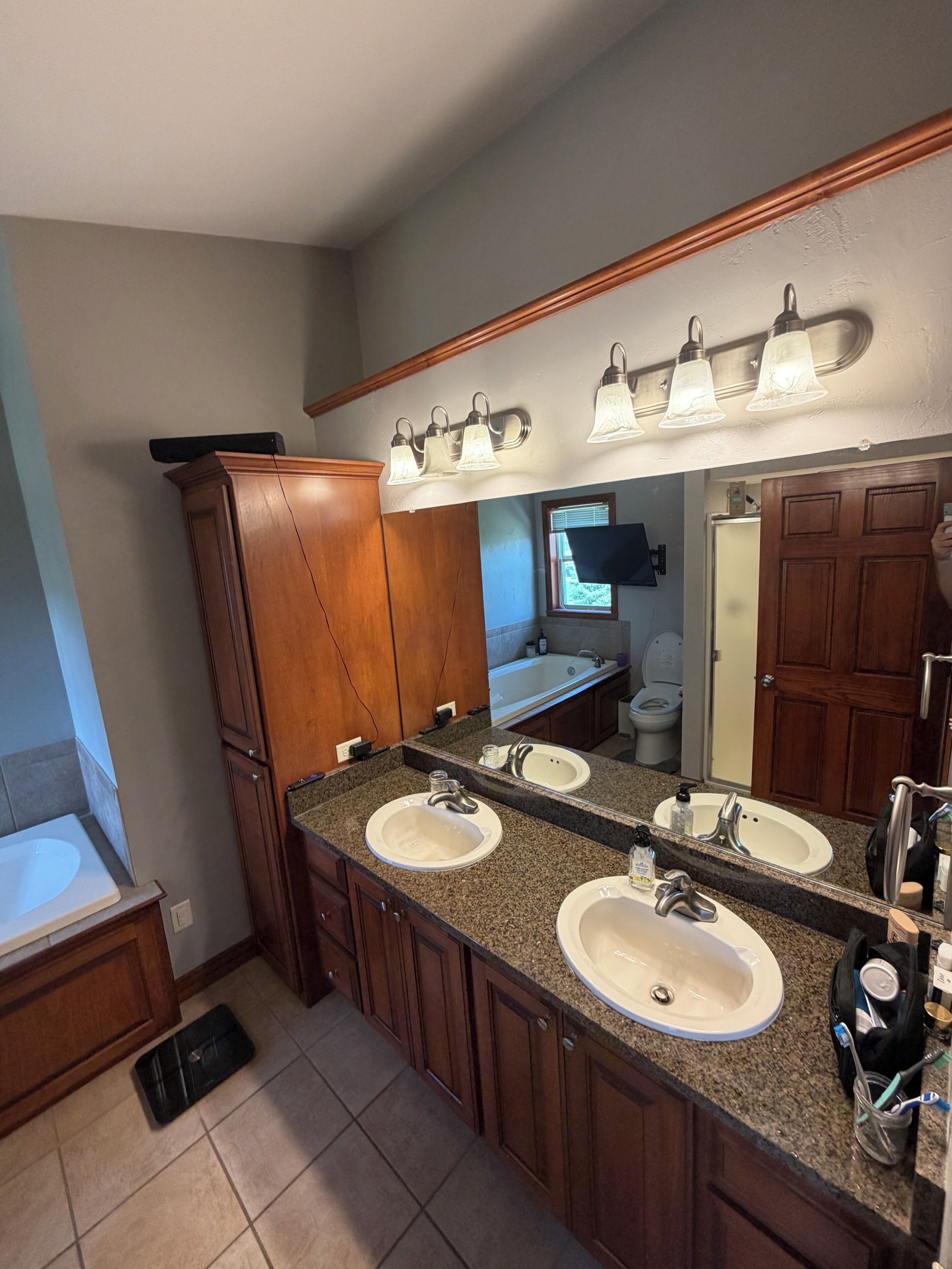 A bathroom with two sinks, a mirror, and a vanity cabinet.