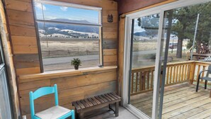 A wooden interior with a bench, a chair, and a window overlooking a landscape.