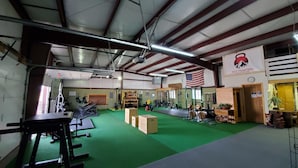 An indoor gym with weightlifting equipment, a green floor, and an American flag.