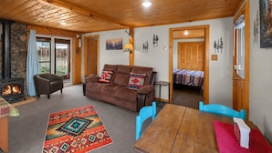 A cozy living room with a fireplace, a sofa, a coffee table, and a dining table.