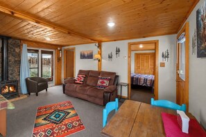 Ein gemütliches Wohnzimmer mit Kamin, einer Couch, einem Couchtisch und einem Esstisch.