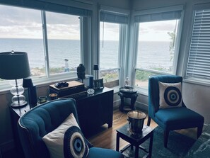 Ein Zimmer mit Meerblick, eine Couch, ein Sessel, eine Lampe und ein kleiner Tisch mit einem Eimer.