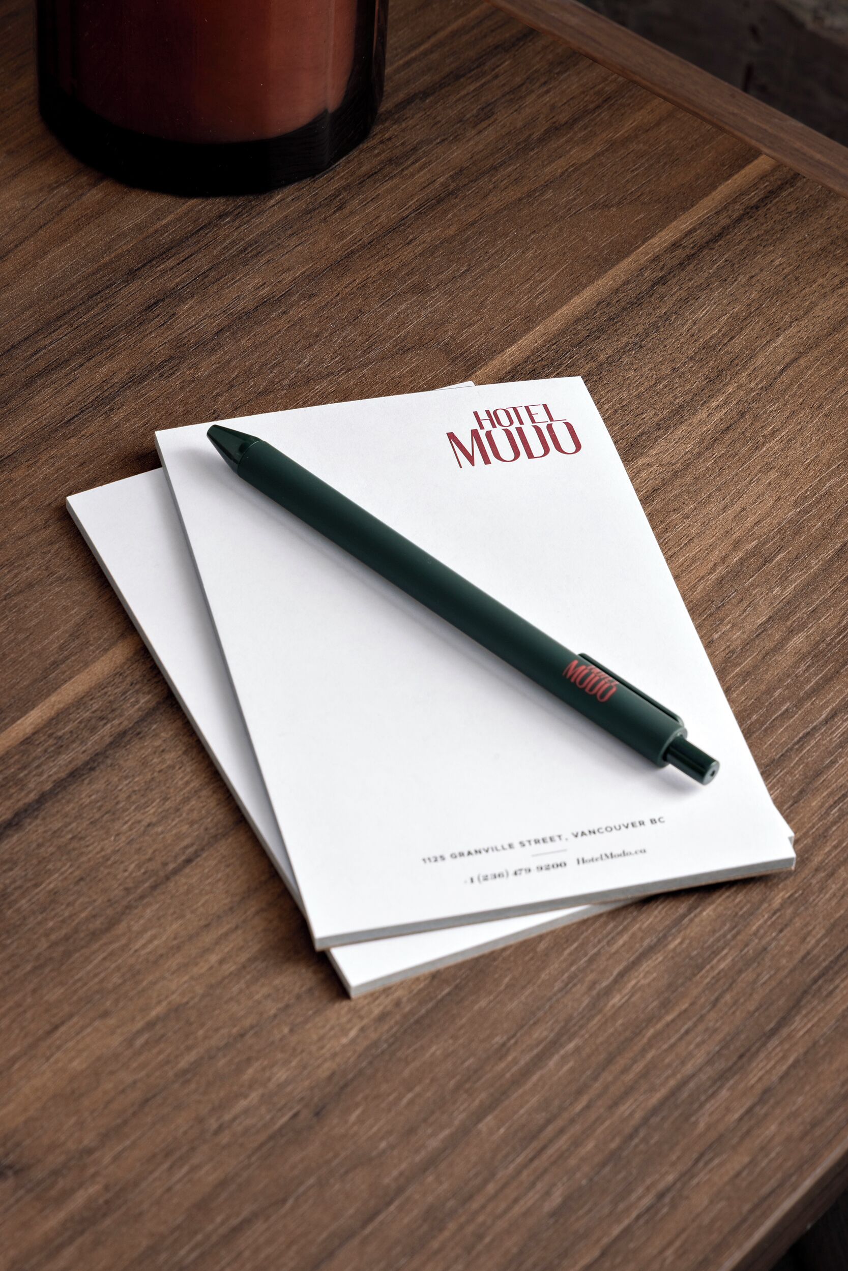 Une brochure intitulée « HÔTEL MODO » est posée sur une table en bois.