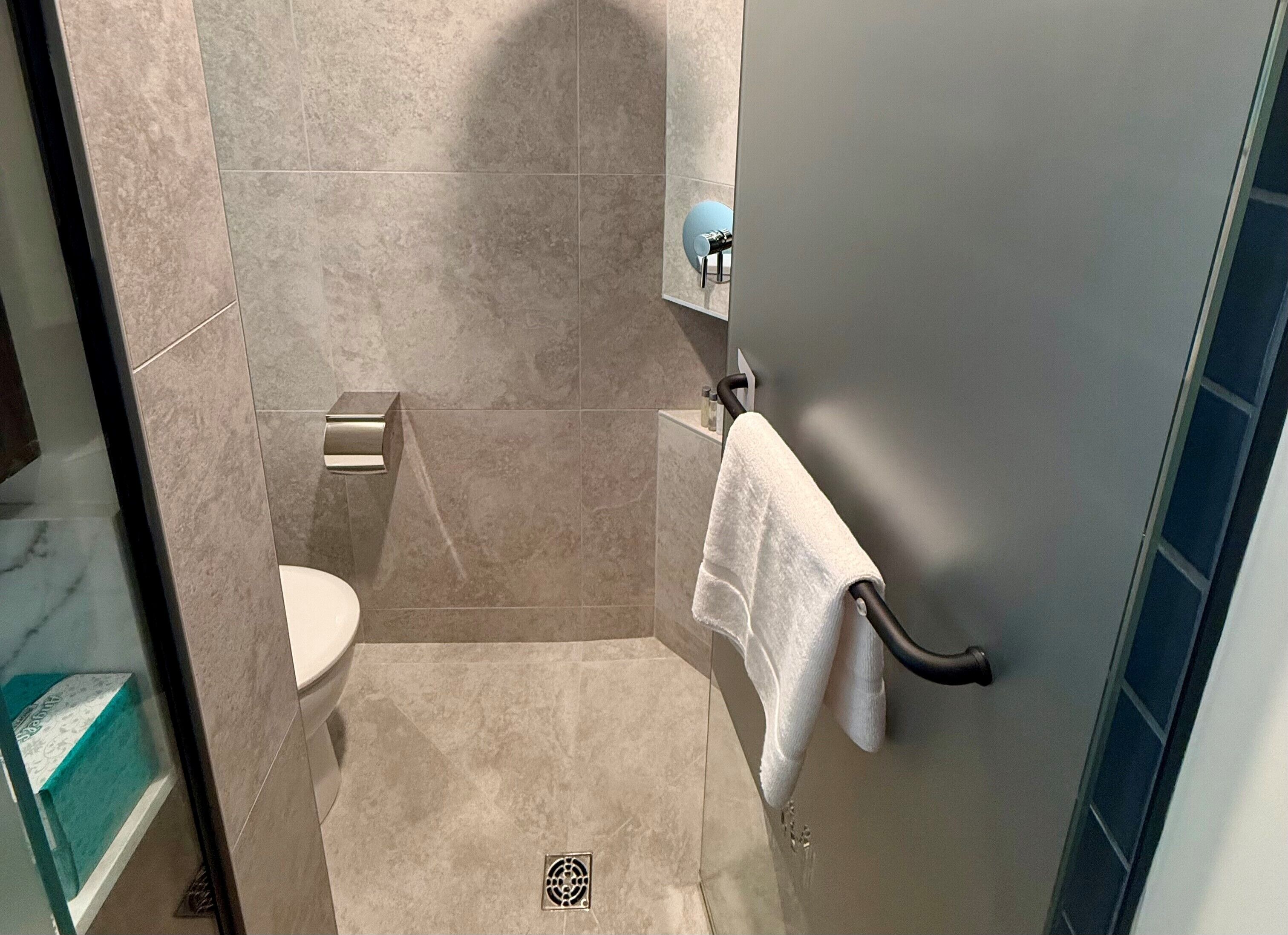 Un baño con inodoro, toallero y zona de ducha.