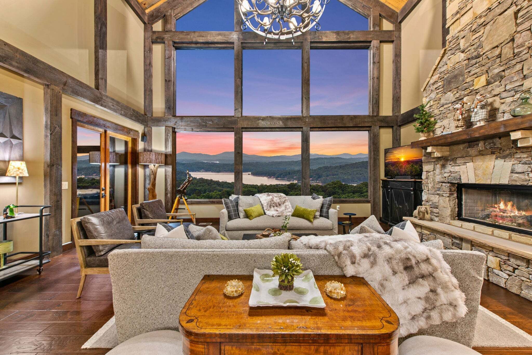 A spacious living room with a stone fireplace, a large window offering a scenic view, and a cozy seating area.