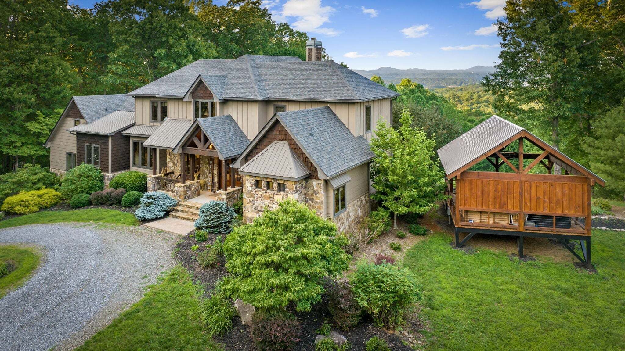 A large house with a stone foundation, multiple gabled roofs, and a wooden deck.