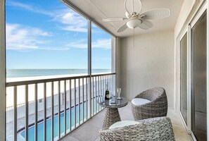Ein Balkon mit Blick auf den Ozean, einem Deckenventilator und Korbmöbeln.