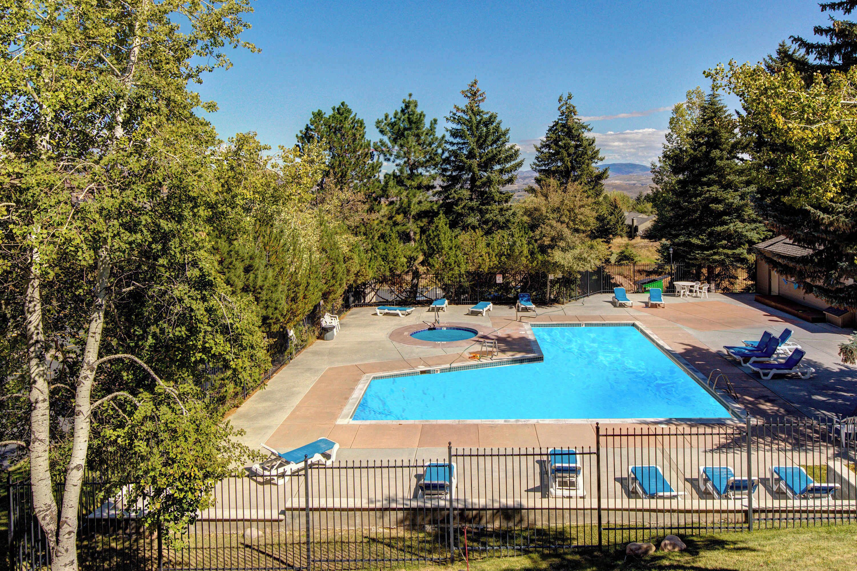 A rectangular swimming pool with a surrounding deck, lounge chairs, and a fenced area.