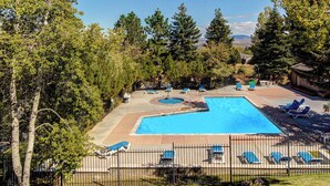 Et rektangulært swimmingpool med terrasse, liggestole og et afspærret område.