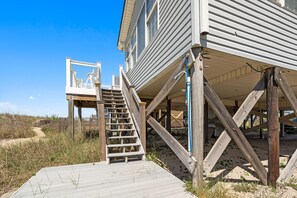 Ein Holzstrandhaus mit einer Holztreppe, die zu einer Terrasse führt.