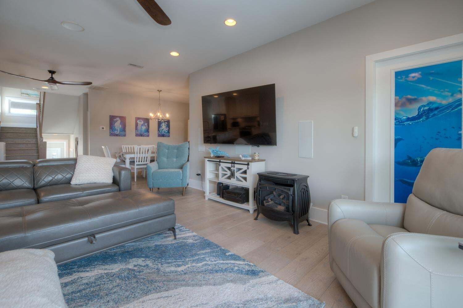 A living room with a sofa, armchairs, a television, a fireplace, and artwork on the walls.