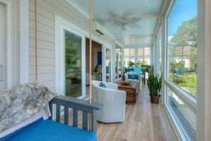 Eine überdachte Veranda mit Deckenventilator, einer Schaukel und einer Sitzecke mit Blick ins Freie.