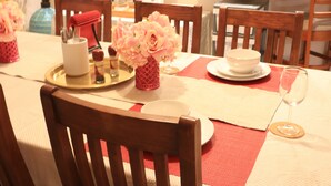 A dining table set with plates, a vase of flowers, and a wine glass. - Duble Room Near Stunning Beaches in quaint Baldivis (Baldivis)