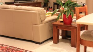 A living room with a sofa, a television, a dining table, and a plant. - Duble Room Near Stunning Beaches in quaint Baldivis (Baldivis)