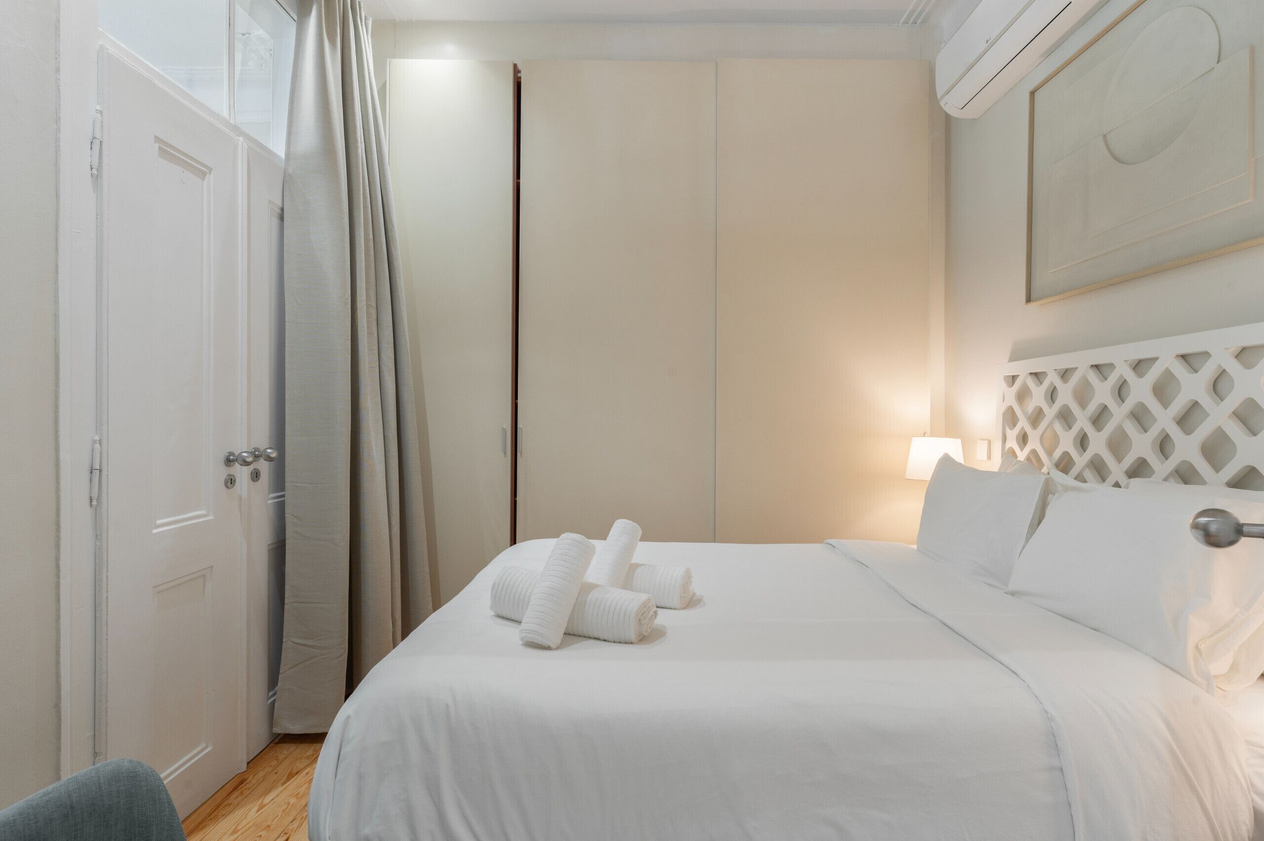 Una habitación de hotel con cama, puerta y lámpara fijada a la pared.