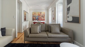 Una sala de estar moderna con un sofá color crema, una alfombra negra y obras de arte en las paredes.