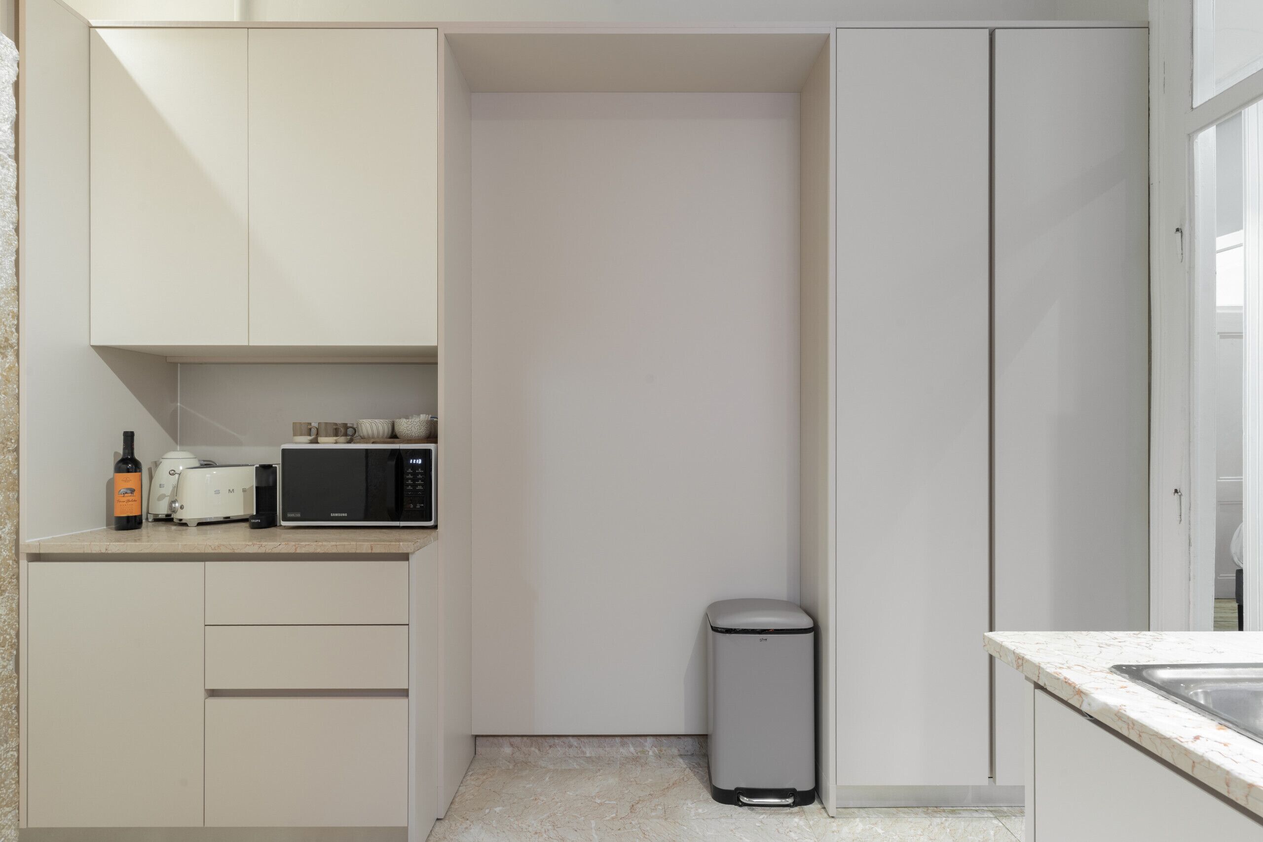 A compact kitchen with a microwave, toaster, and trash bin.