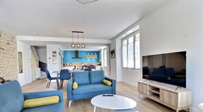Ein modernes Wohnzimmer mit einer Couch, einem Fernseher und einem Essbereich im Hintergrund.