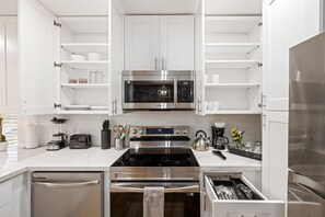 A modern kitchen with white cabinetry, stainless steel appliances, and a central island with a sink. - Pet-Friendly Montrose 1BR | Museums| Free Parking newly renovated M2 (Houston)