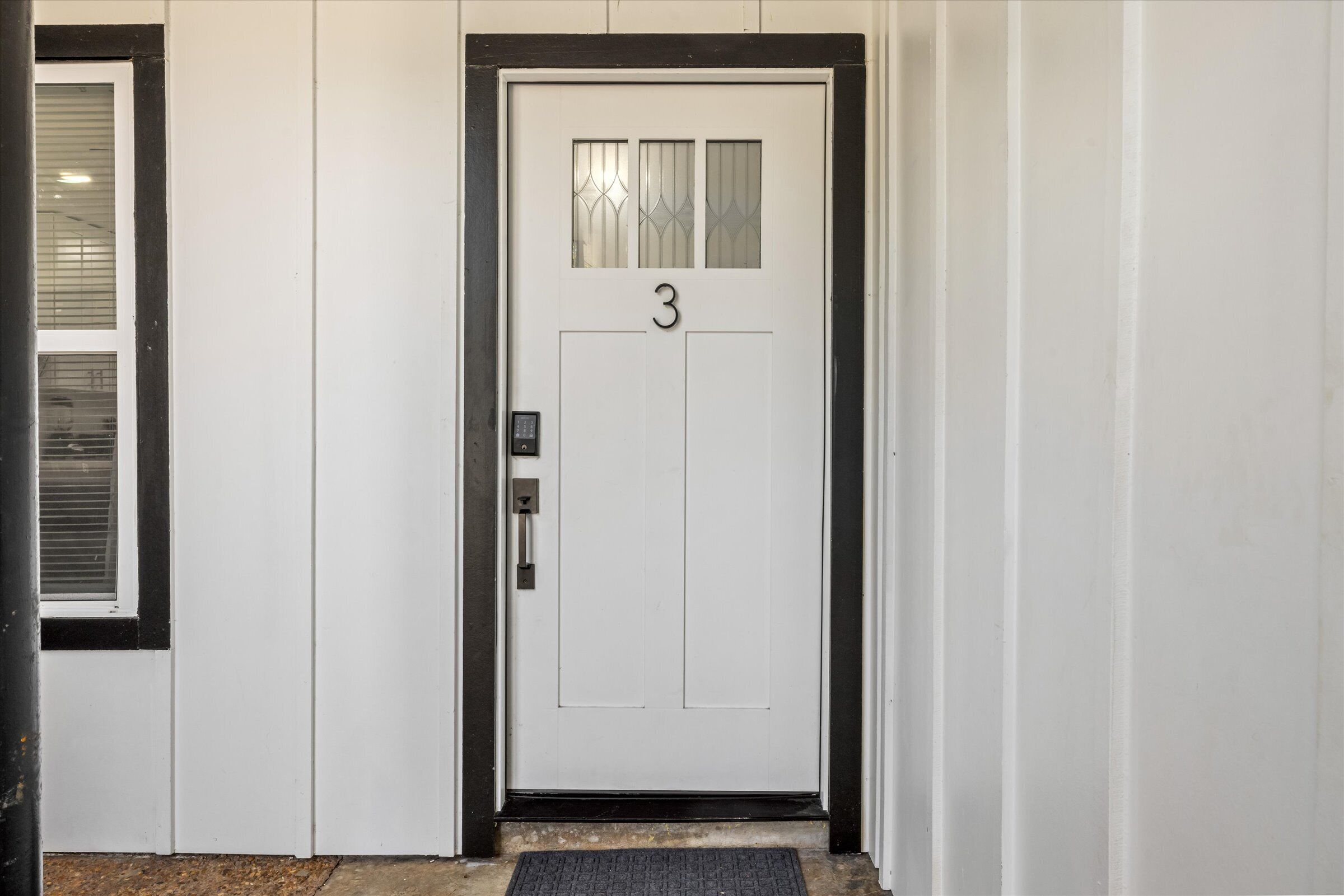 A white door with the number 3, a small window, and a doorbell.