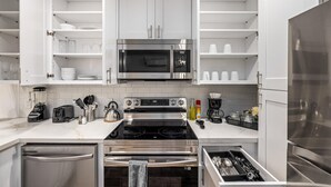 Een moderne keuken met witte kasten, roestvrijstalen apparatuur en een marmeren aanrecht.