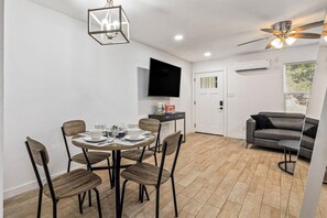 A modern living room with a dining area, a flat-screen TV mounted on the wall, a ceiling fan, and a window with blinds. - Great Location, near Coffee shops<br>Pet-Friendly, 1BR | Museum District | Free Parking<br>newly renovated (Houston)