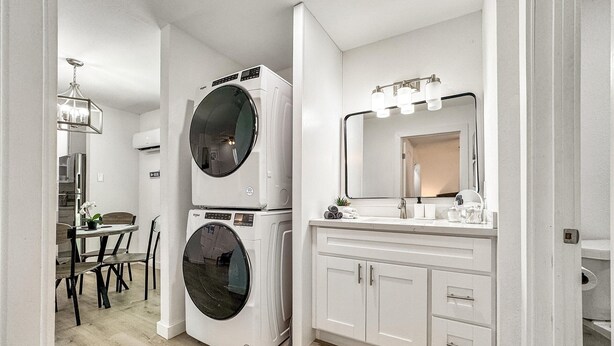 Une salle de bain moderne équipée d’un lave-linge-sèche-linge combiné, d’un meuble-lavabo avec miroir et d’un coin repas comprenant une table et des chaises.