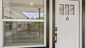 Una puerta blanca con el número 6 y una ventana con persianas.