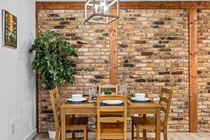 A dining area with a brick wall, wooden table, and chairs. - Pet-Friendly Montrose 1BR | Museum District | Free Parking<br>newly renovated (Houston)